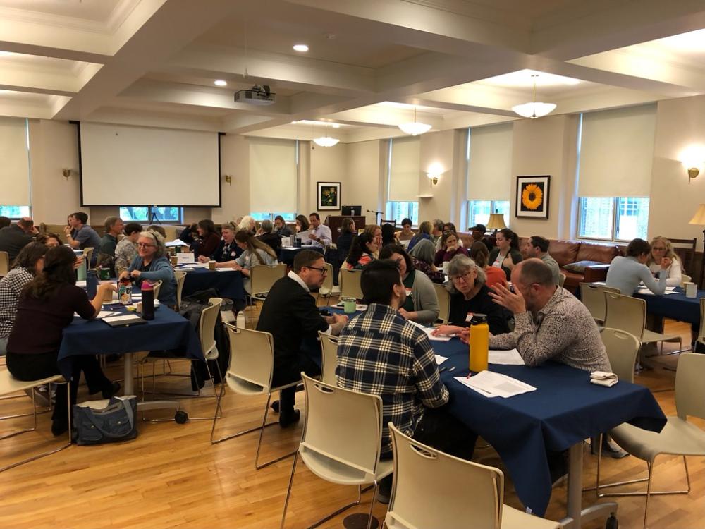 Several large groups sitting around tables during a tech-free teaching workshop
