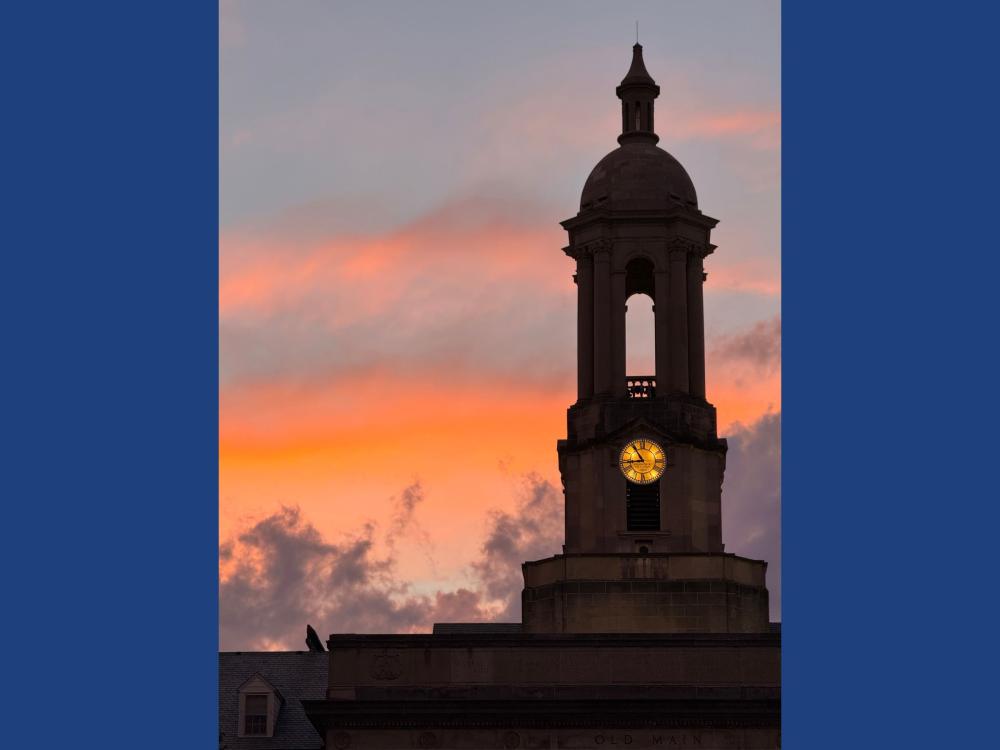 A bell tower with a clock at sunset