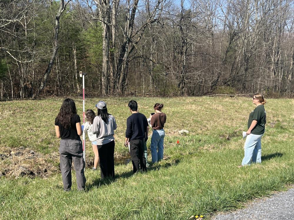 Students measuring a waterway's slope using a laser level.