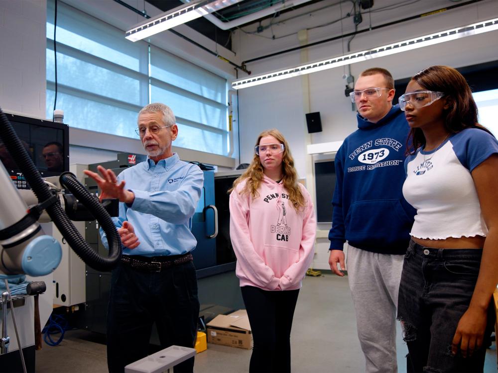 Terry Speicher teaches a small group of students in front of a piece of equipment. 