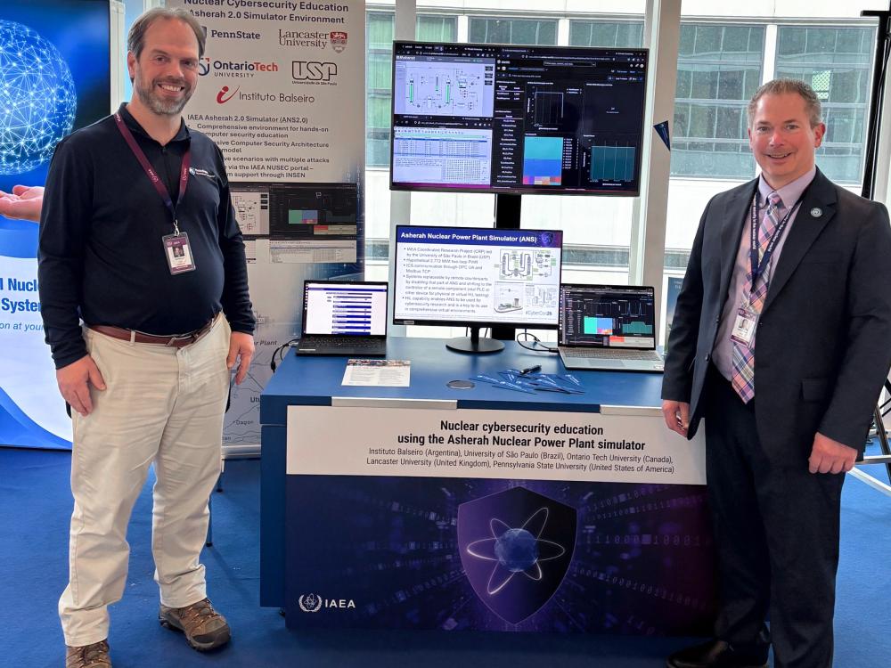 Gary Meyers and Matthew Zerphy pose next to a booth at CyberCon26