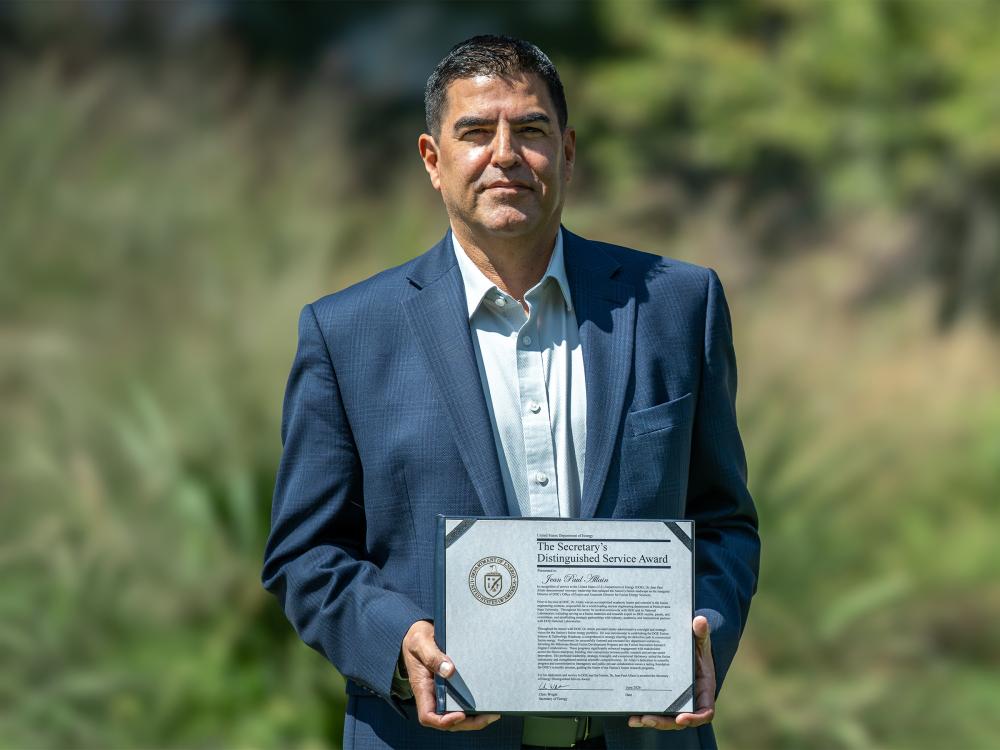 Jean Paul Allain poses outdoors with an award plaque.  