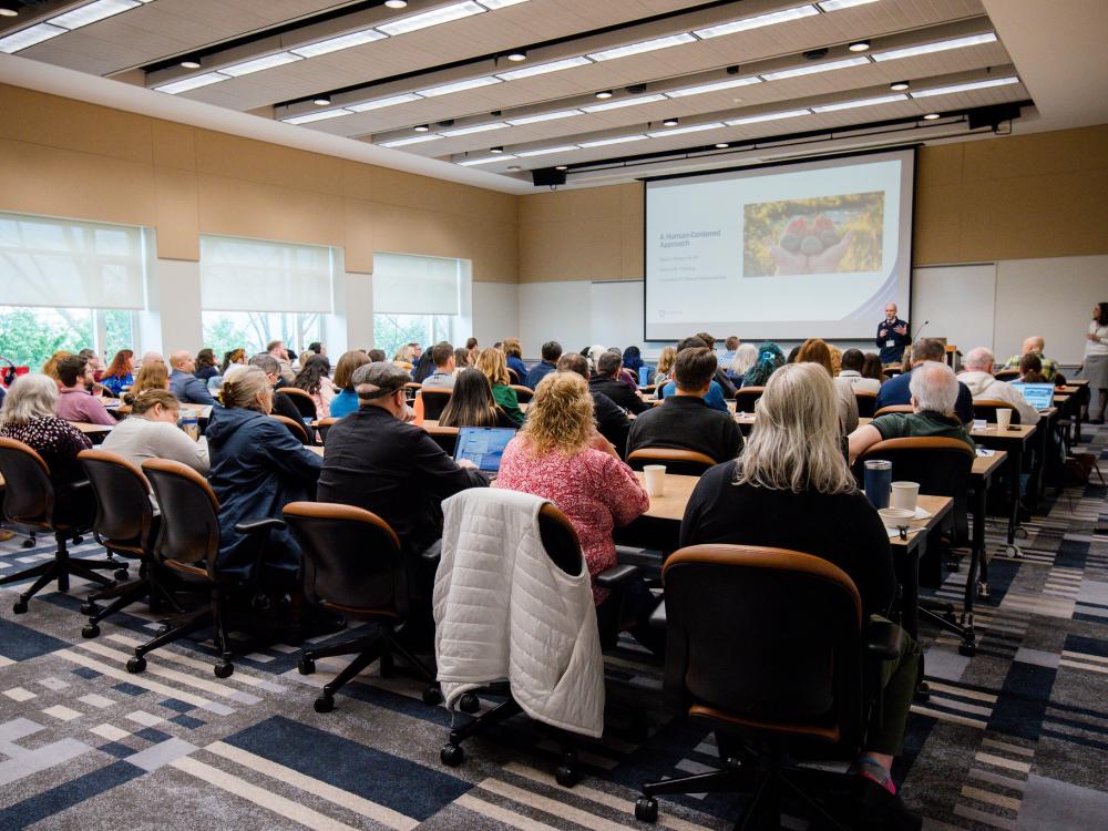 Symposium attendees listening to a presentation on AI at Penn State at the Penn Stater Hotel and Conference Center.