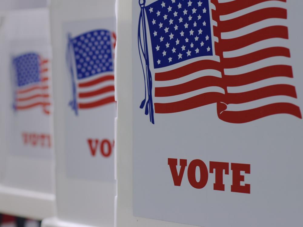a row of voting booths with an American flag pictured on the sides of booths