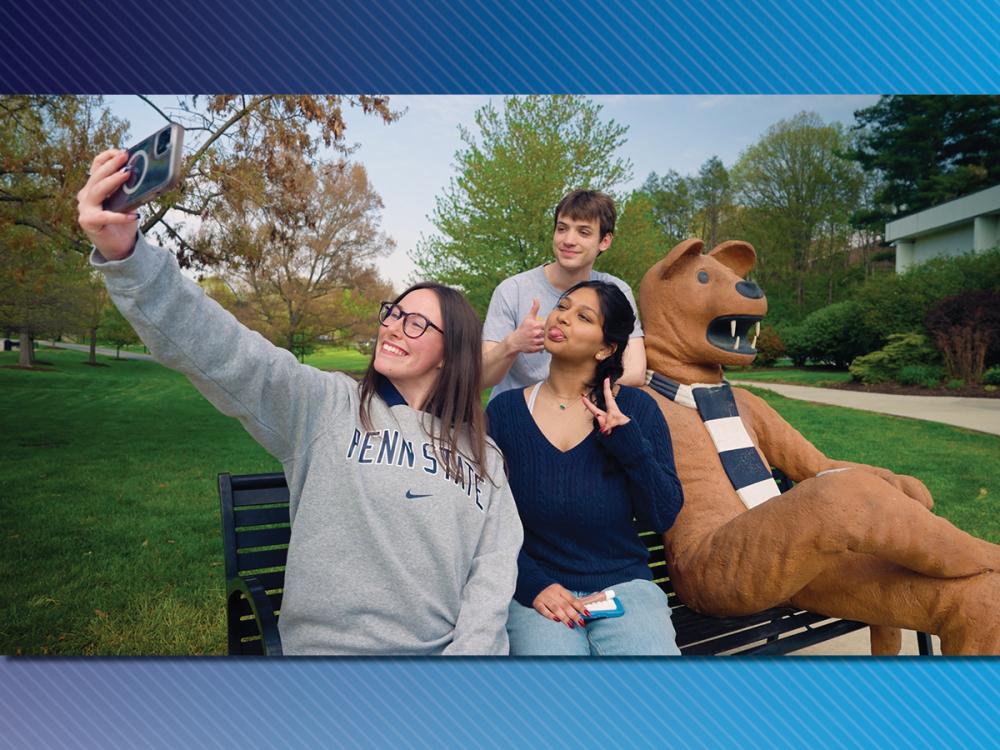 Three students take a selfie with the Penn State Berks Lion Bench