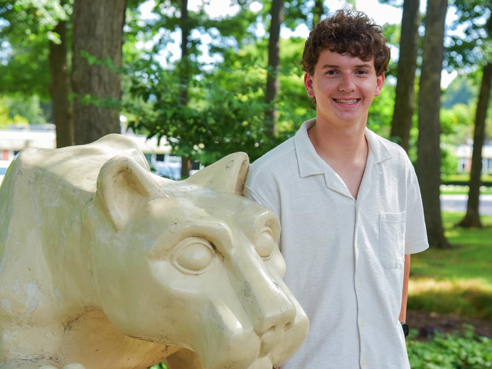 Evan Wagenmann poses beside the Nittany Lion Shrine on the Penn State Altoona campus.