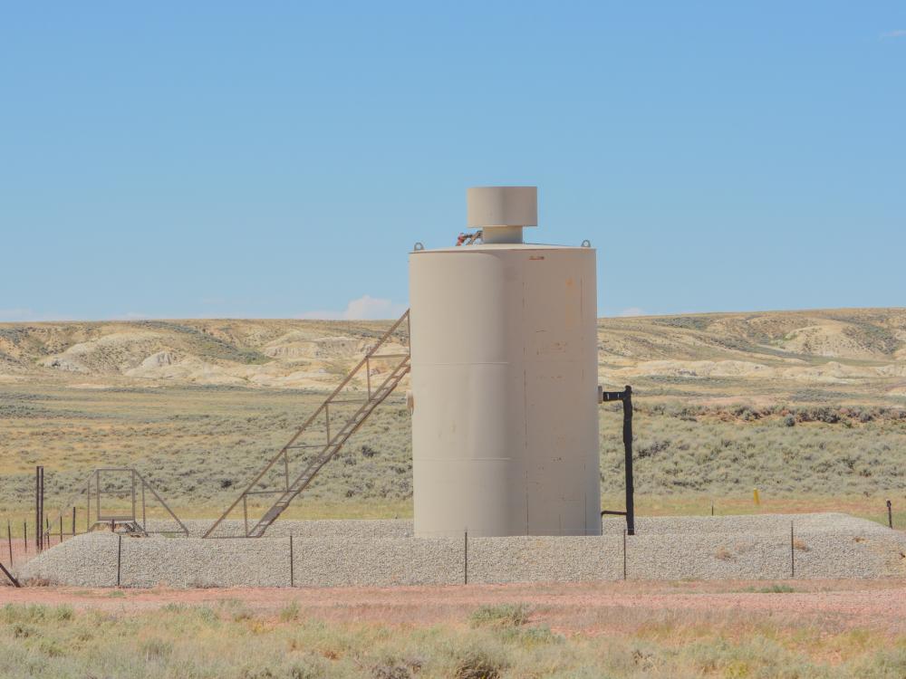 gas well equipment sits with a barren landscape from the American West in the background