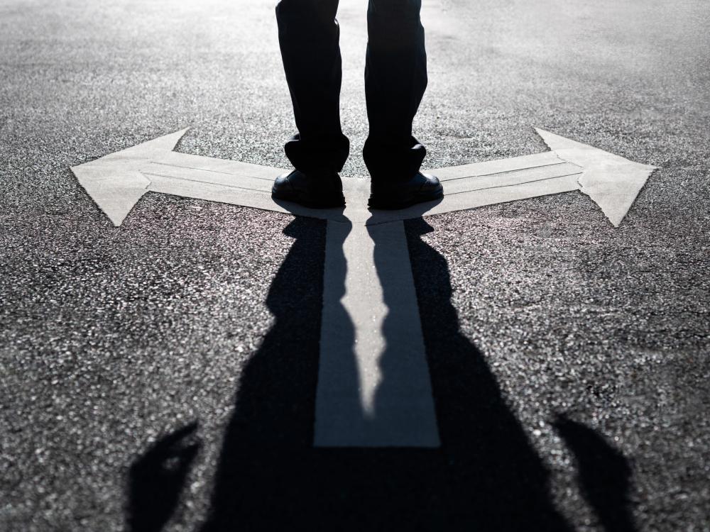 person's feet standing on arrows at fork in the road