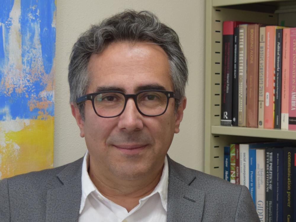 Man with curly graying hair and dark-rimmed glasses