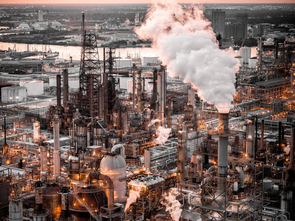 Dimly lit industrial plant with plumes of white smoke releasing from smokestacks