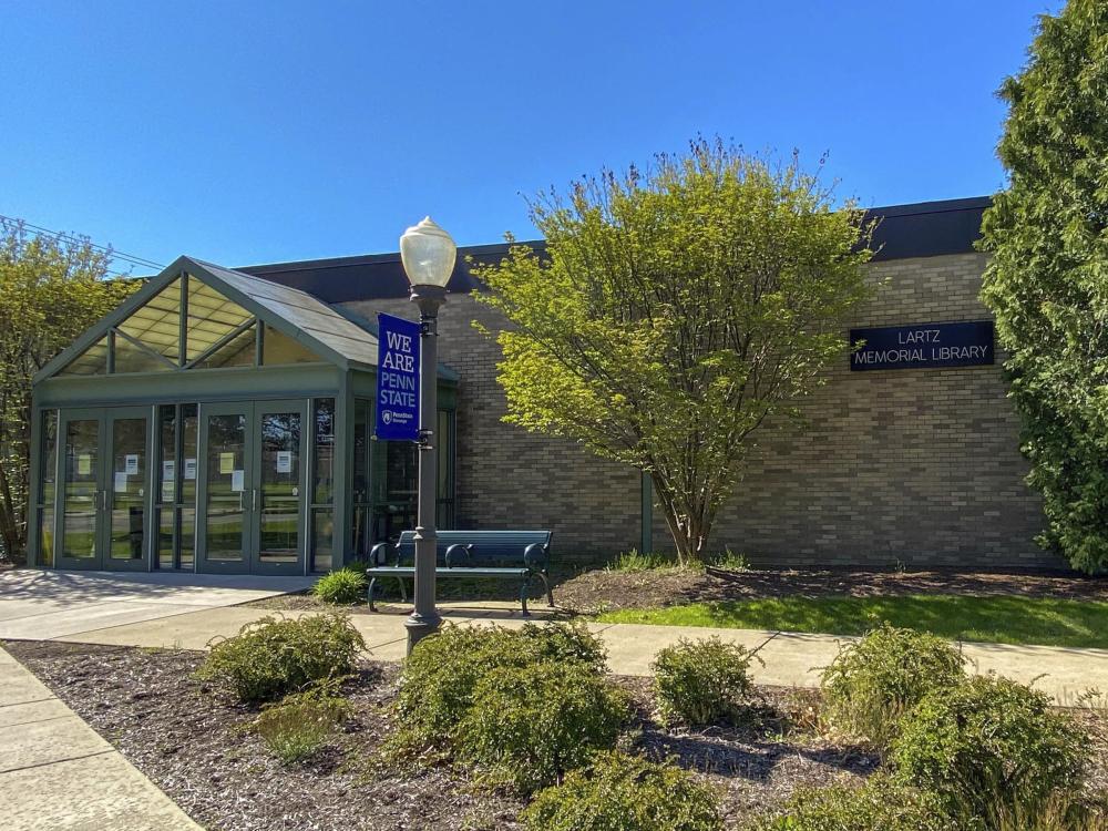 Lartz Memorial Library exterior with trees, landscaping, and blue sky.