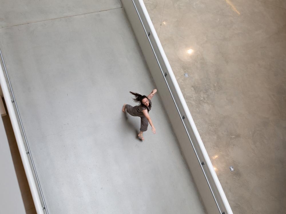 Lauren Linder dances barefoot in an indoor campus atrium.