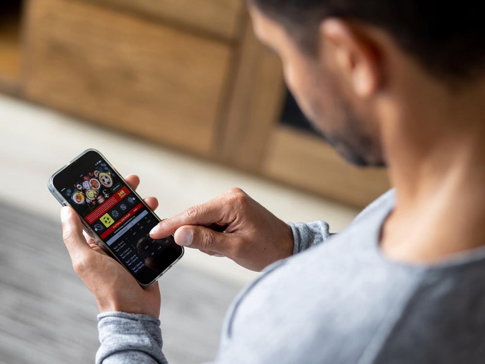 Man gambling online on a football game using his cell phone.