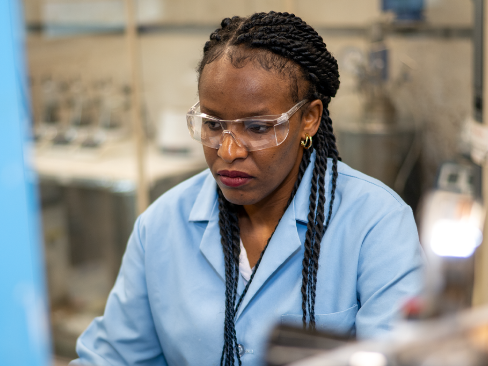 Melissa Gonte wearing a blue lab coat and safety glasses in a lab.