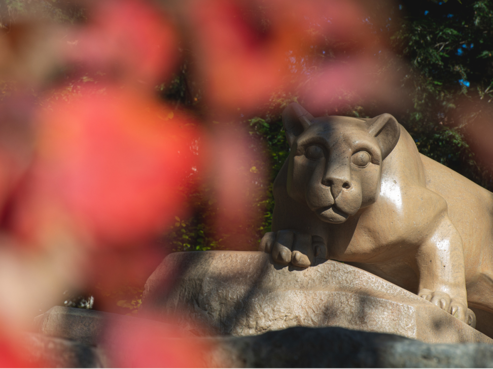 Nittany Lion Shrine at right with blurry red foliage at left.