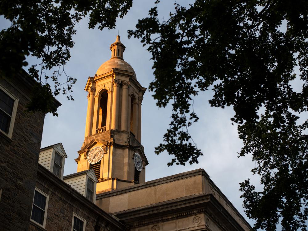 Old Main's bell tower lit up gold by the setting sun