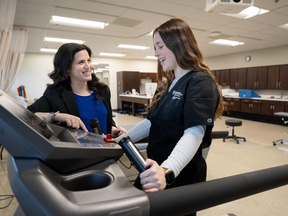 Two women work together on treadmill doing physical therapy