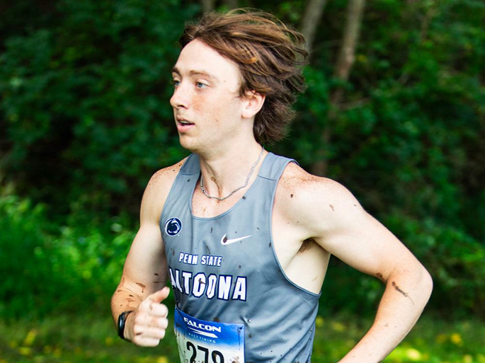 Remy Bailey runs outdoors in a Penn State Altoona uniform during a cross-country race.