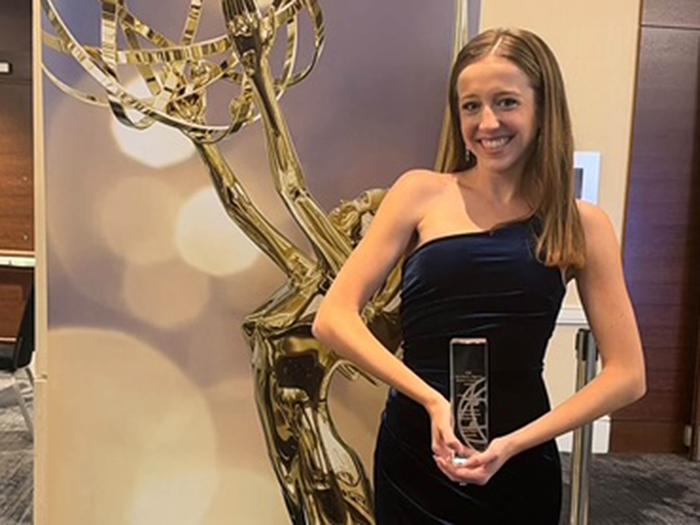 Smiling woman in black dress holds a crystal award
