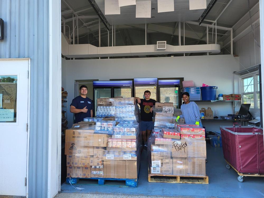 Students at the Lion's Pantry pose with palettes of donated goods.