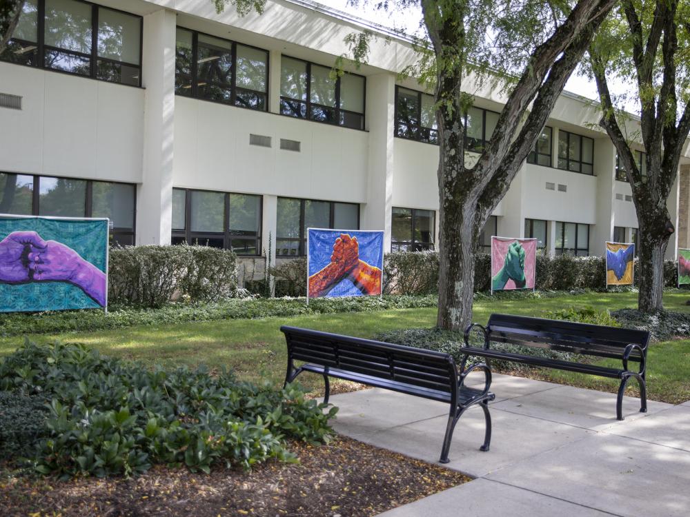 Five color murals of hands grasping one another in front of Perkins Student Center