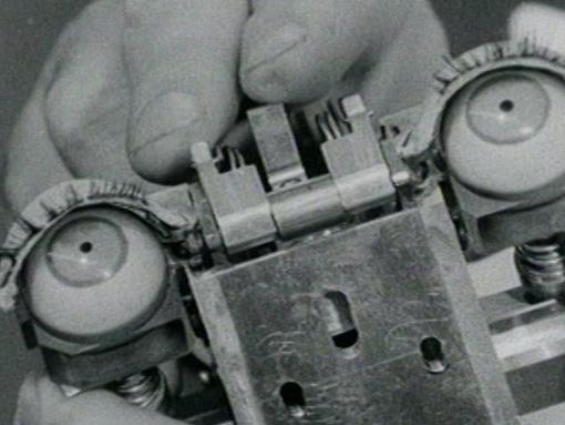 Still image from Ghost in the Machine of an AI precursor with two fake eyeballs in black and white