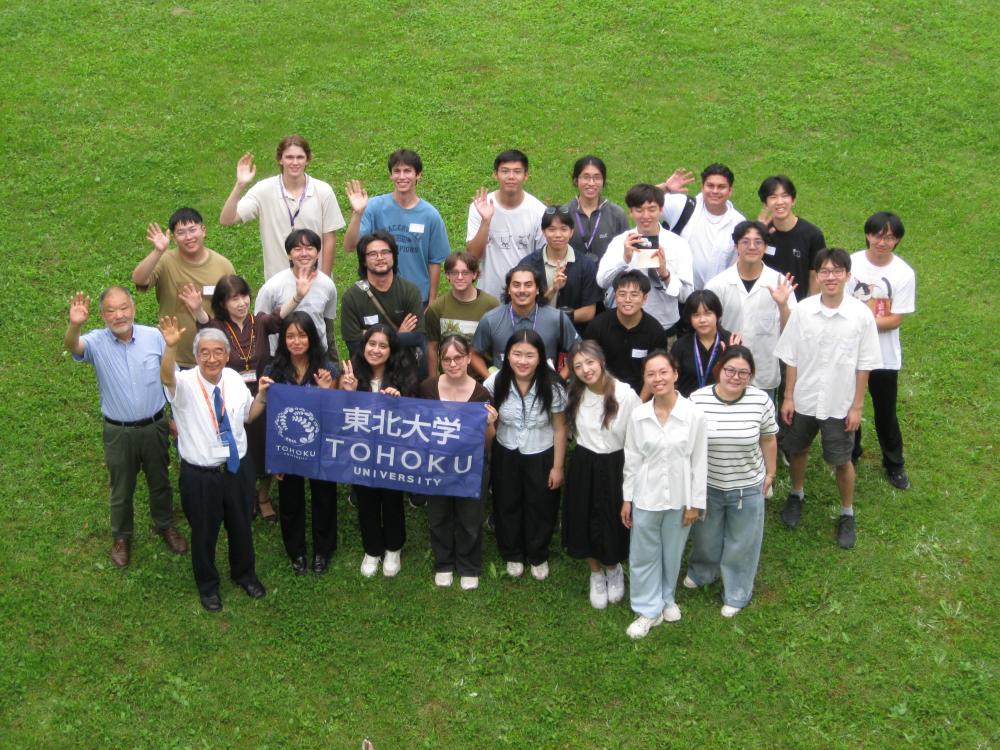 A group stands with a Tohoku University banner for a picture