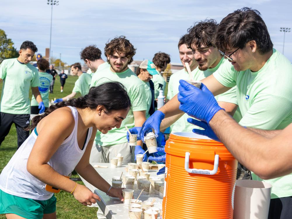A participant grabs a cup of ice cream from a table.