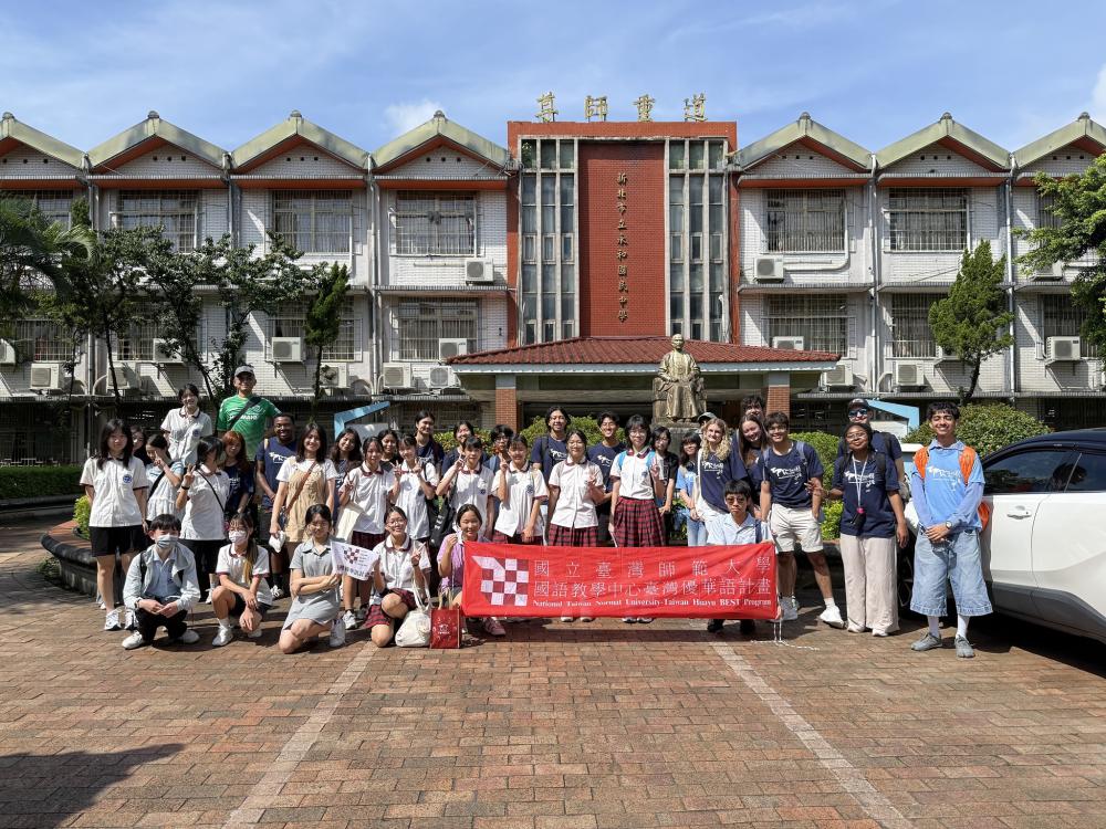 A group of students stand for a picture with a National Taiwan Normal University Banner