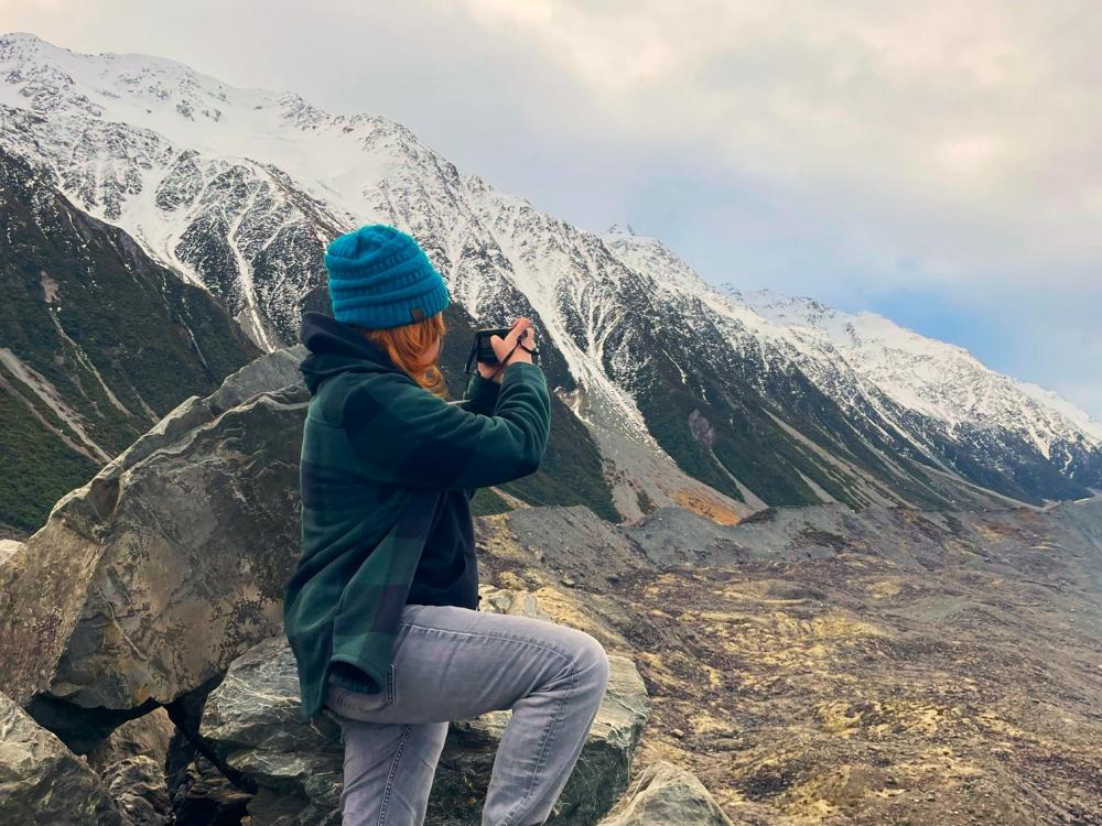 A young woman in a mountainous region holding a camera