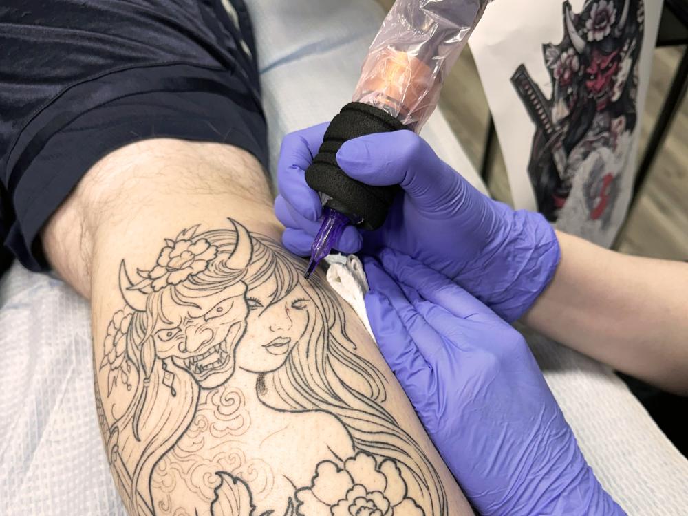 Tattoo artist working on client