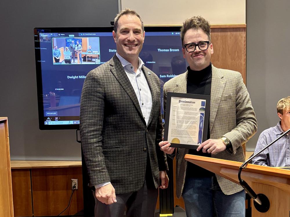 Two men standing side by side with one holding a framed document.