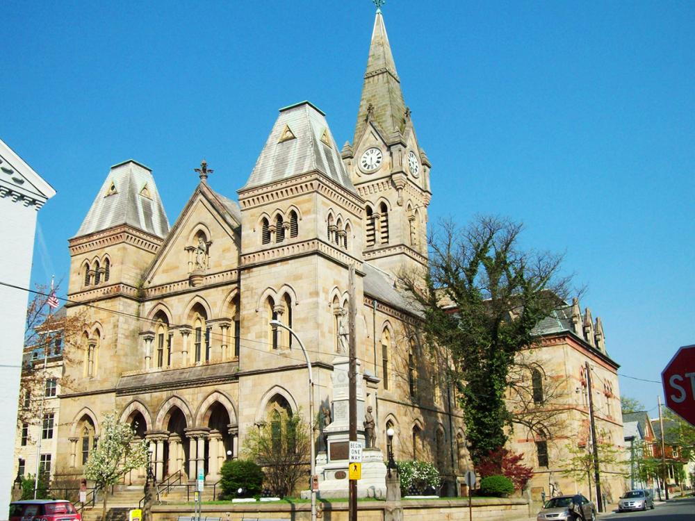 Blair County Courthouse in Hollidaysburg, Pennsylvania, with ornate stone towers and a clock tower beneath a clear blue sky.