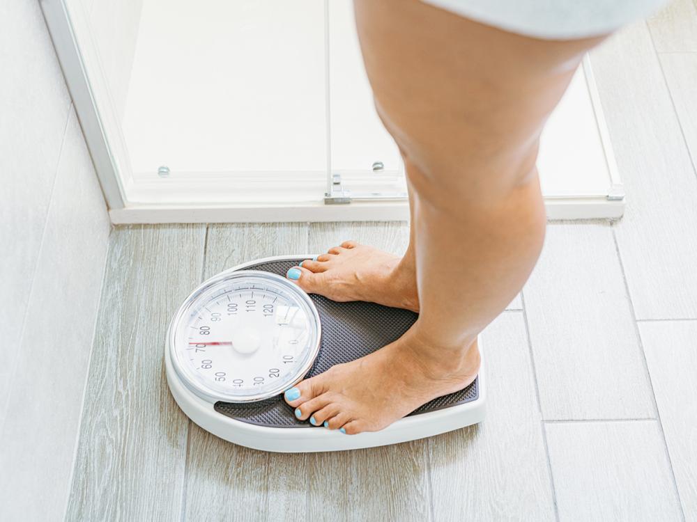 High angle view of a woman standing on a weight scale in a bathroom.