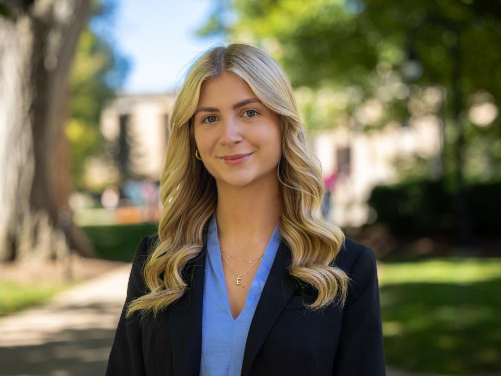 Erin Gregorian wears a black blazer over a blue shirt while standing outdoors.