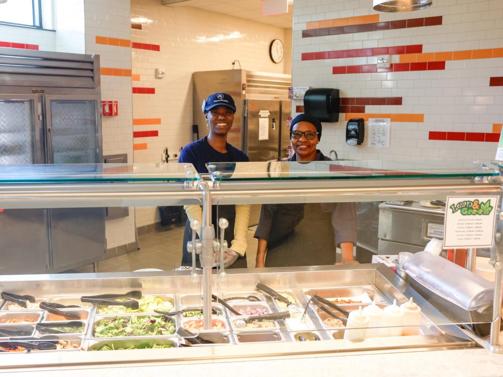 Two blue apple café workers standing behind the halal offerings at Brandywine