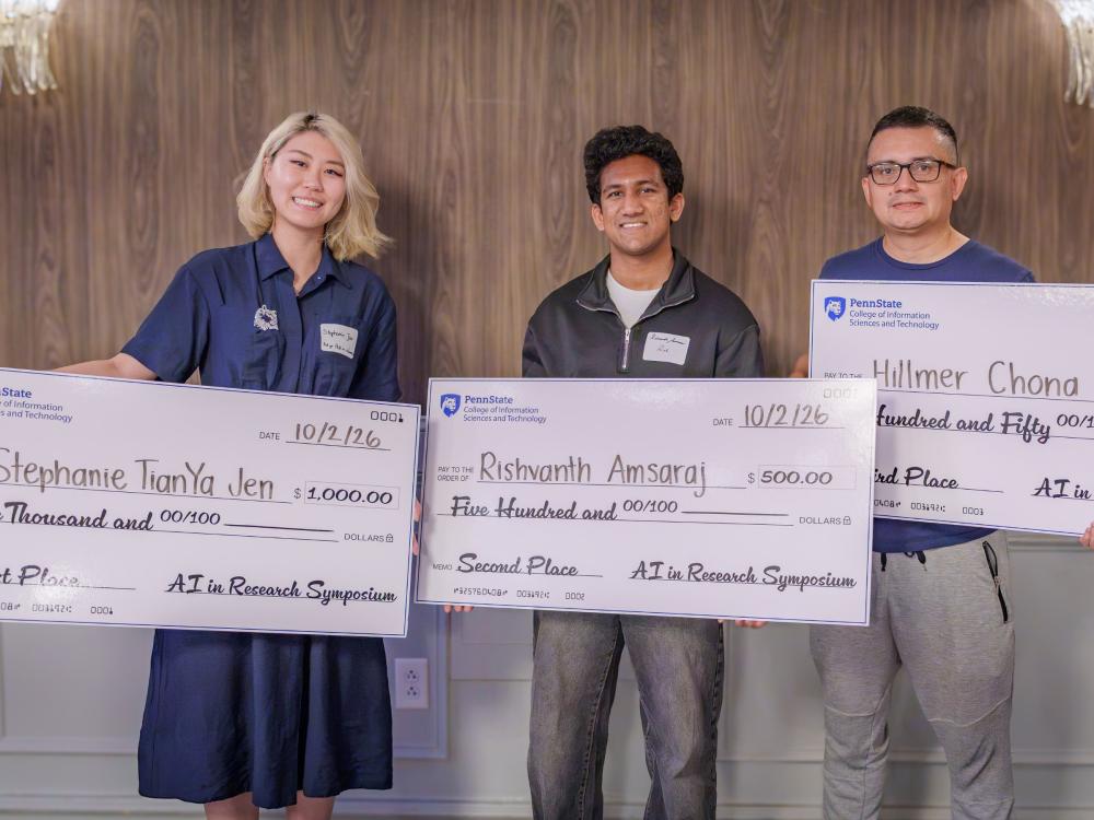 three people hold giant checks
