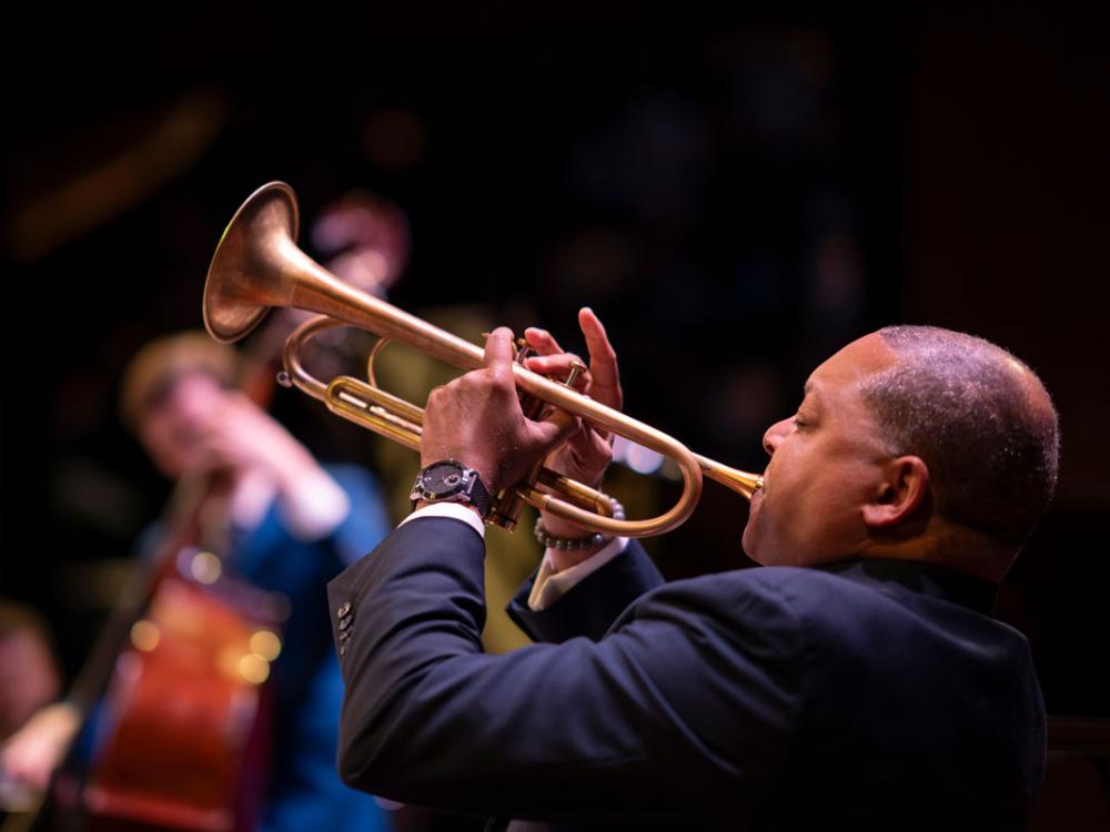 A Black man plays a trumpet.