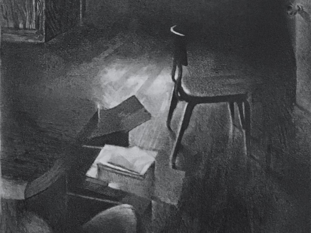 Grainy black-and-white image of a dim interior, with a seated figure beside a chair and a box on a nearby surface.