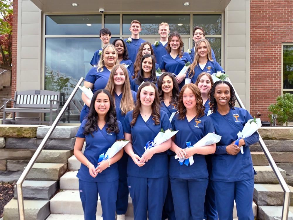 a group of nursing students pose in their blue nursing uniforms on the steps of the Penn State Scranton's nursing facility