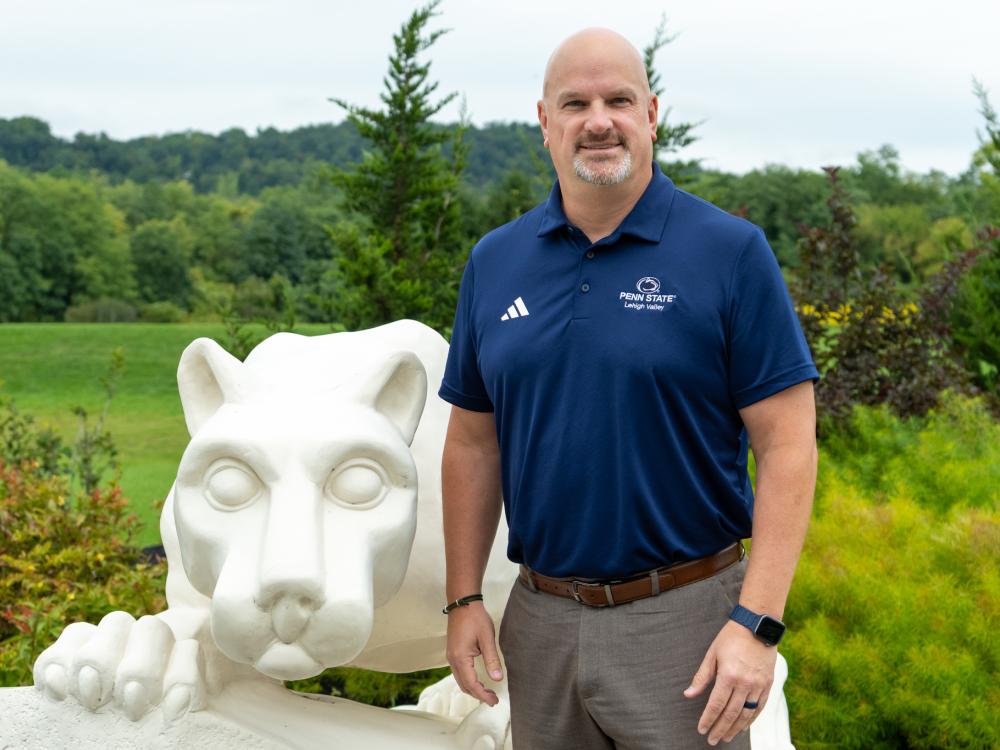 John Vandevere stands next to Nittany Lion Shrine