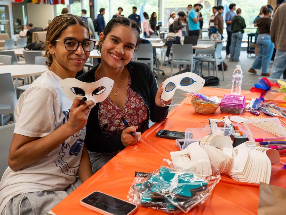 two girls at a table holding a mask