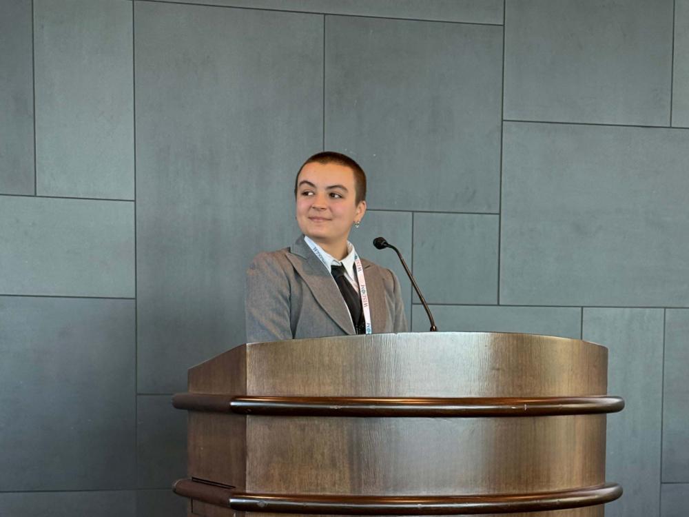 girl standing at podium looking to her right during a presentation