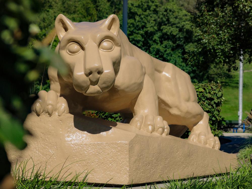 A Nittany Lion shrine stands among trees and landscaping on the Penn State Greater Allegheny campus.