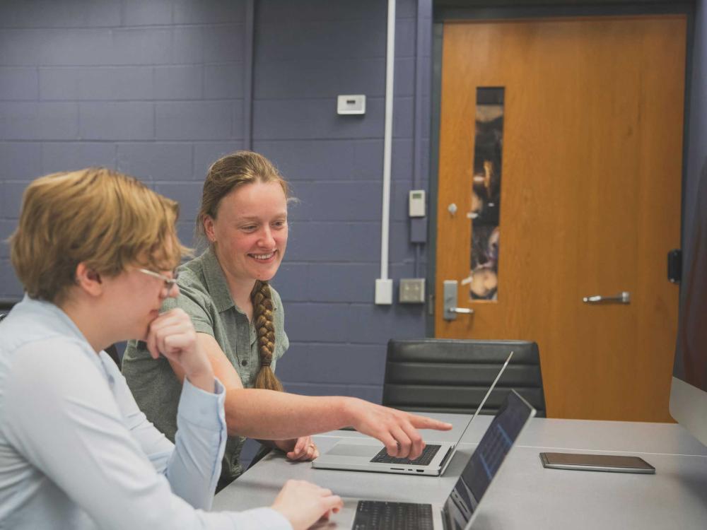 Charlotte Ward, sitting next to student in her lab, points to computer