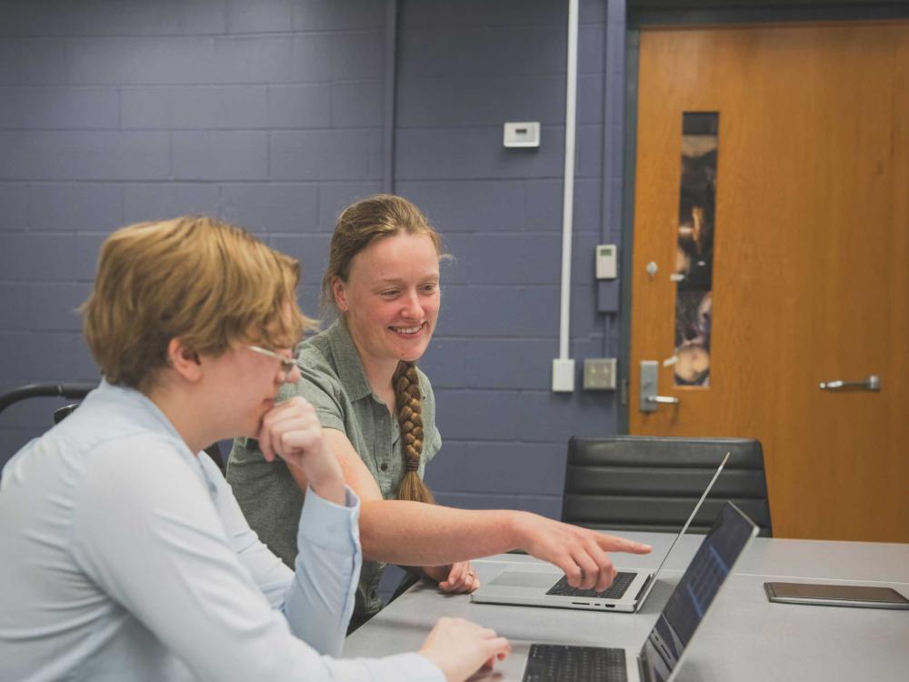 Charlotte Ward, sitting next to student in her lab, points to computer
