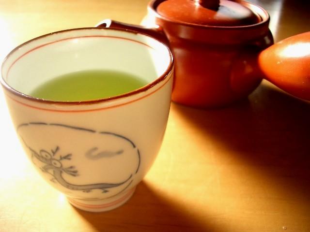 red teapot with green tea in a white cup