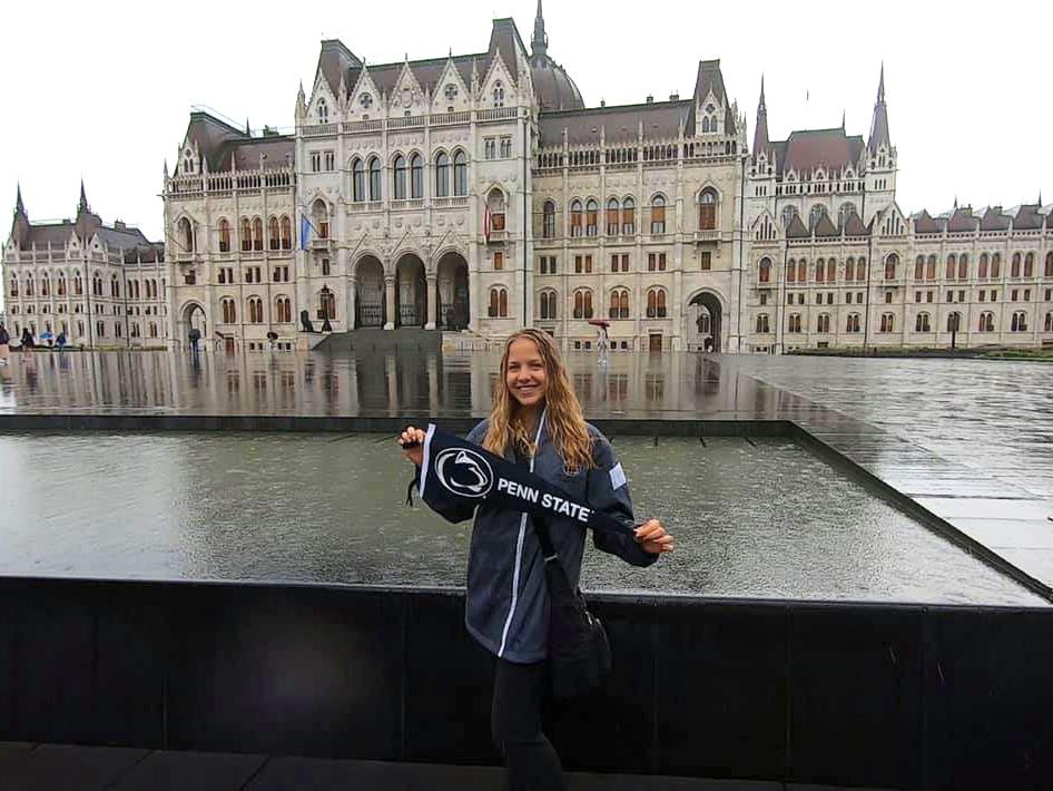 Student holding Penn State Flag in front of water feature