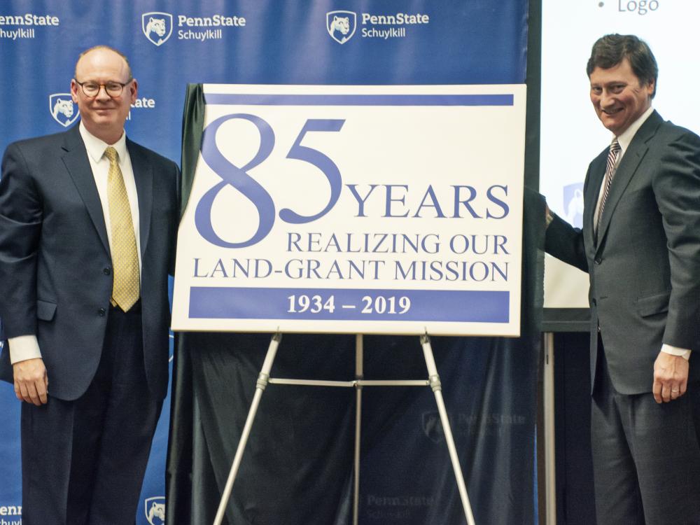 Chancellor Patrick Jones and Schuylkill advisory board member Richard Wiest unveil the 85th anniversary logo