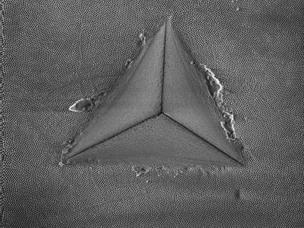 A nano-porous anodic aluminum oxide membrane after nanoindentation showing shear banding behavior around an indentation impression.
